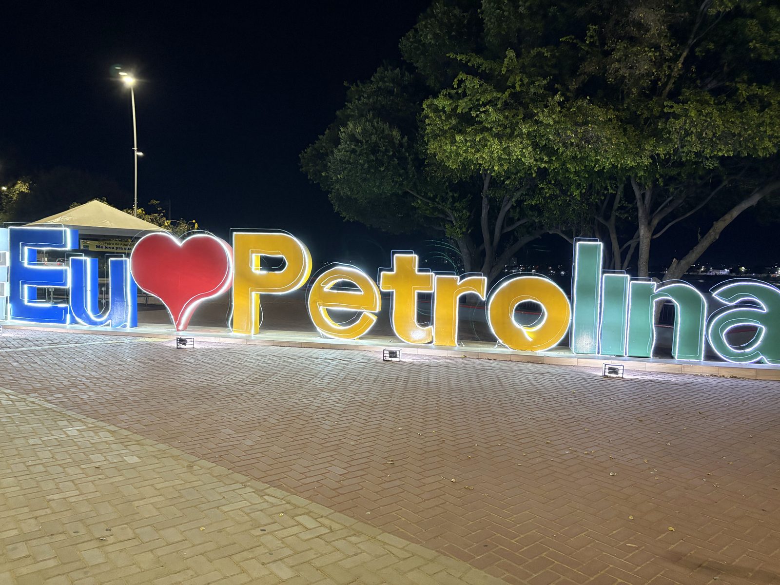 Orla de Petrolina vista do rio, com prédios, palmeiras e o céu do sertão
